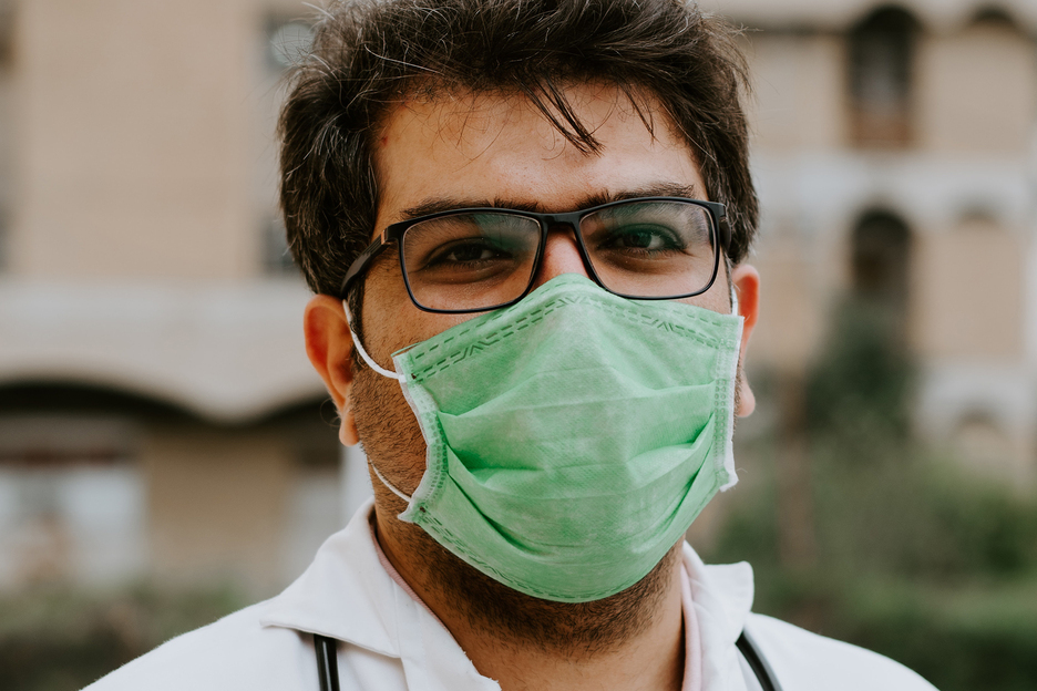 Doctor with glasses wearing a green face mask.